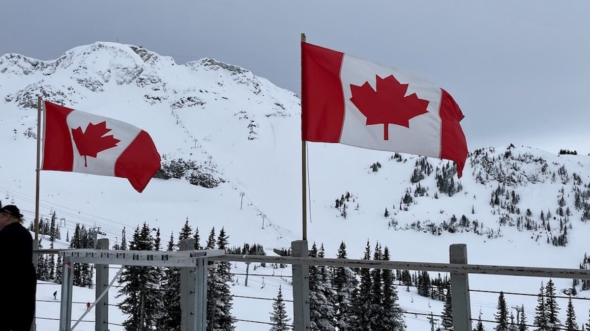 Top of Whistler Ski Resort and Canada flags blowing in the wind on snowy day