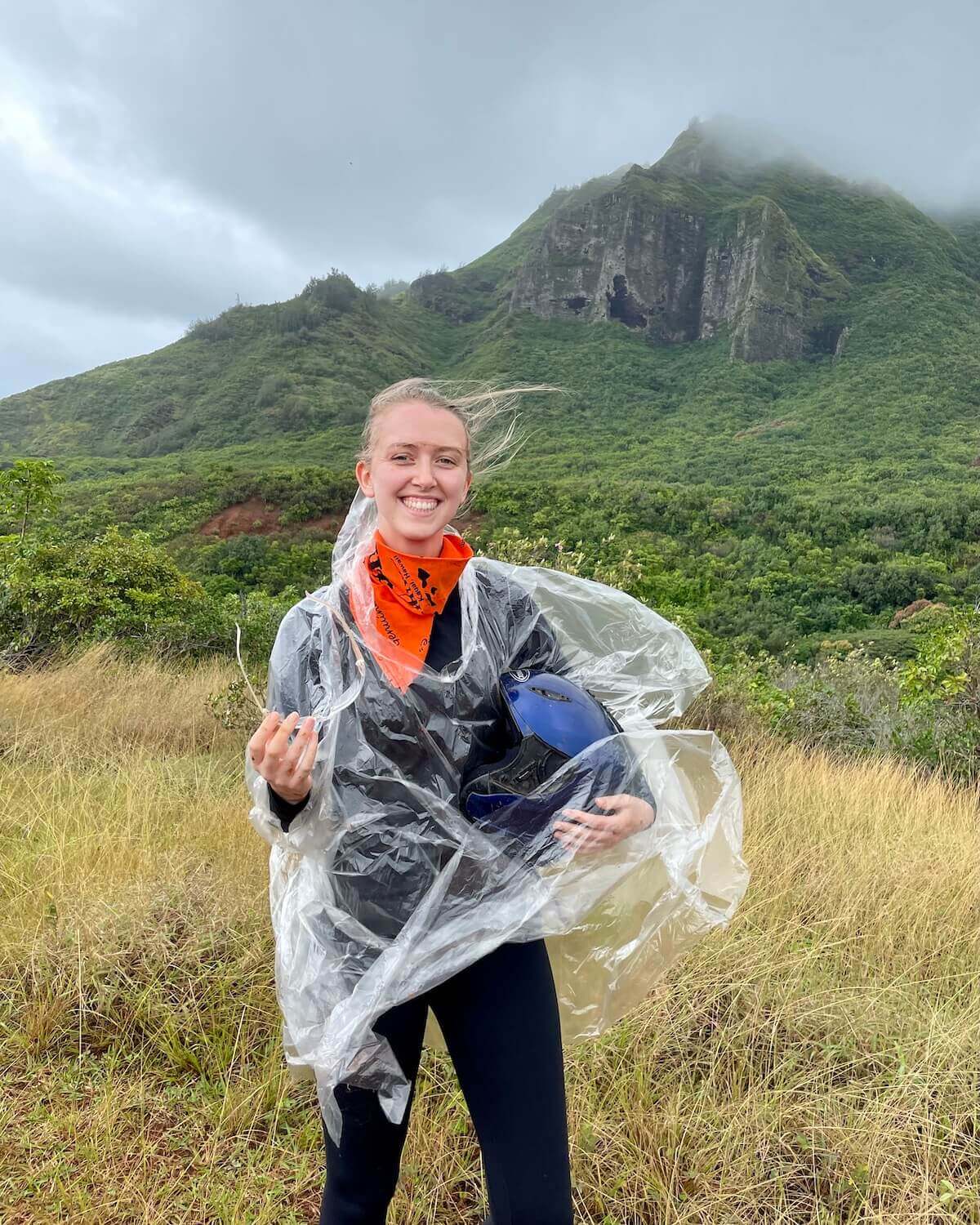 Samantha covered in mud from Kipu Ranch wearing poncho and holding helmet