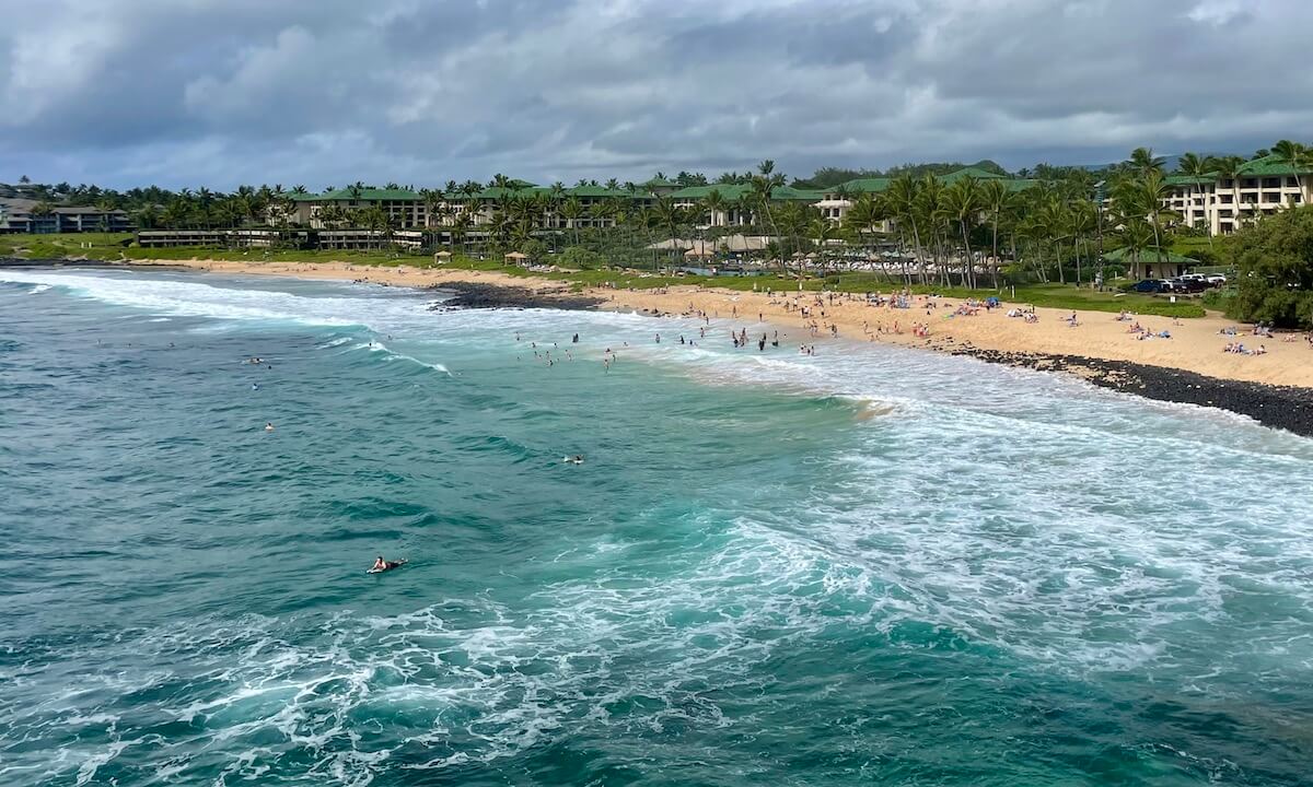 Shipwreck Beach in winter - surfer and sunbathers Kauai