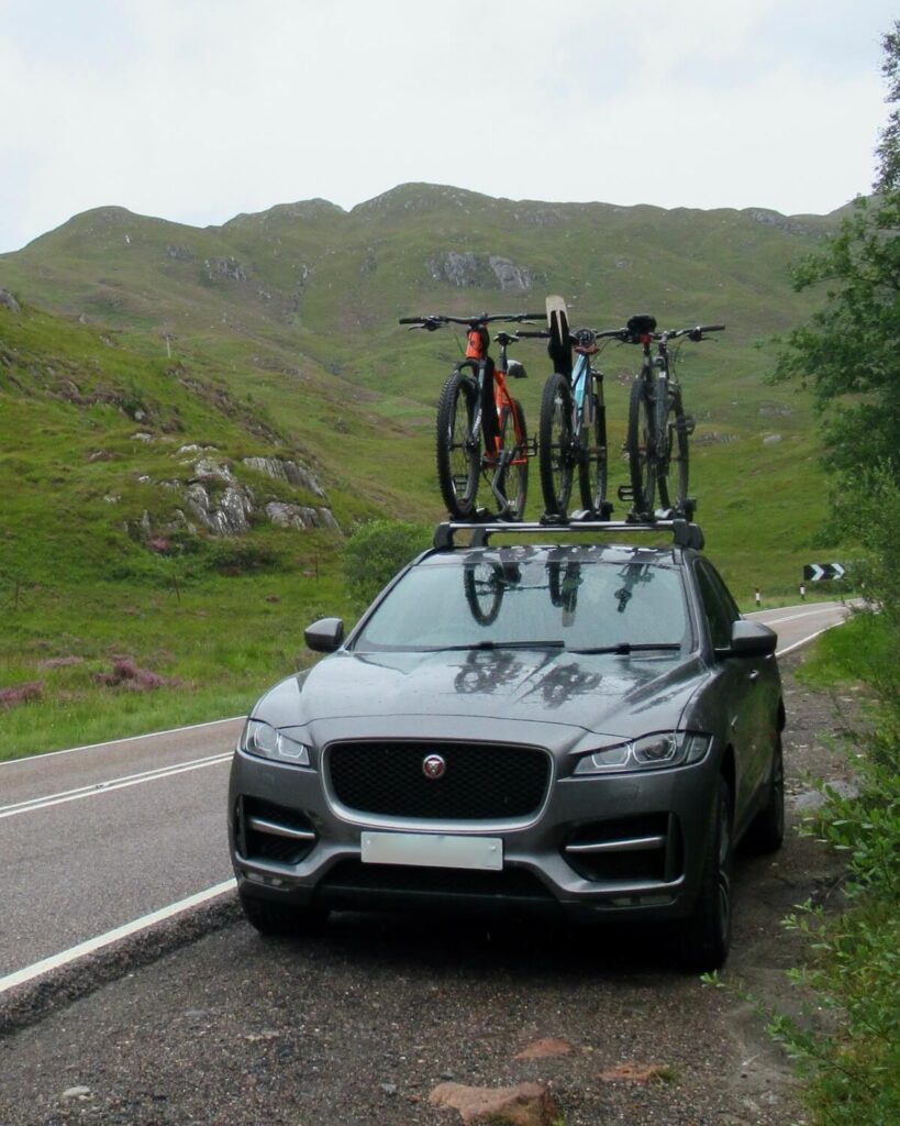 Jaguar car with bikes on top in layby in Scotland