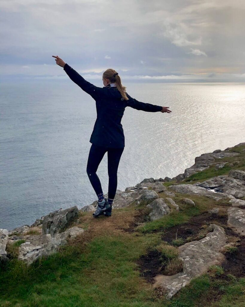 Samantha standing on Neist Point Lighthouse at sunset