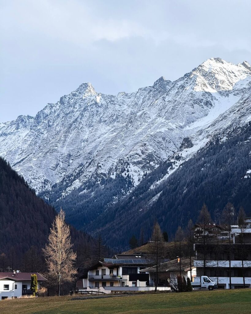 Wooden lodges in Solden with snowy mountains in backdrop