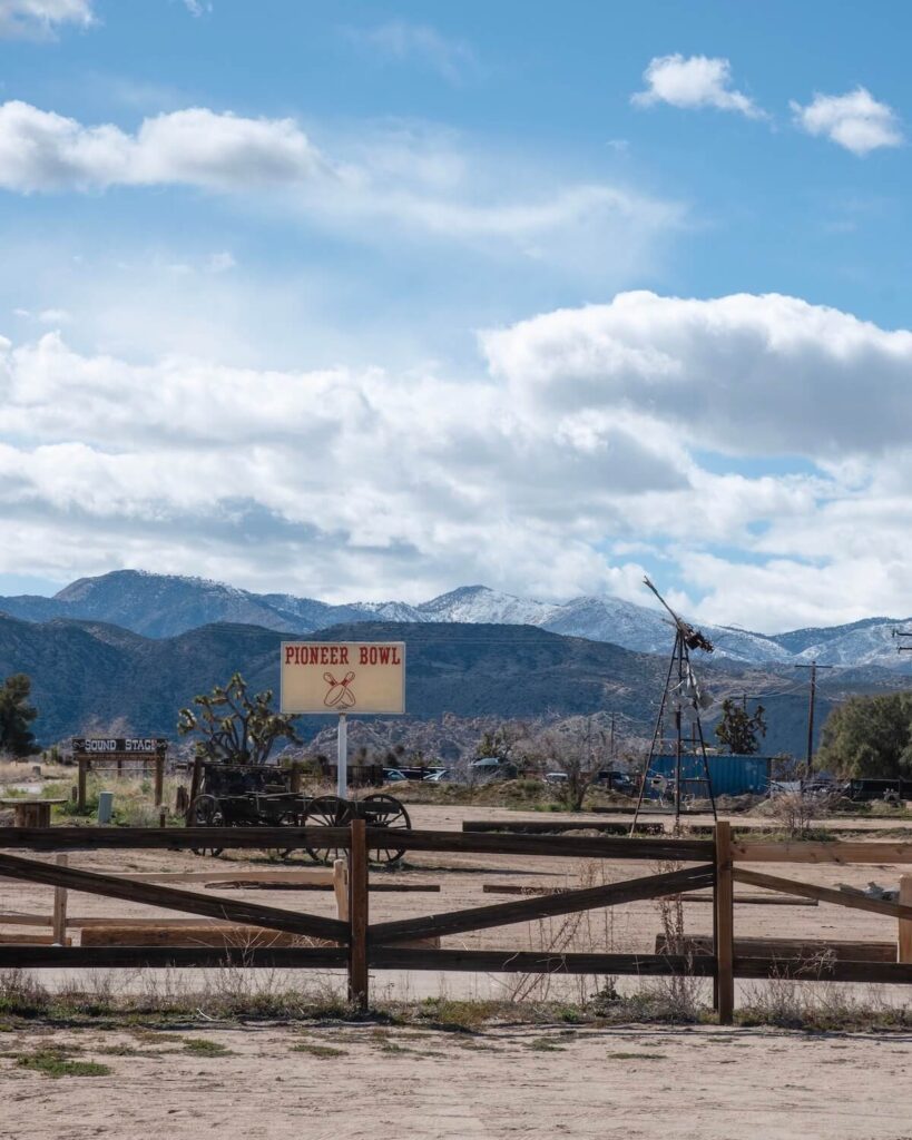 Snowy mountains in distance over fence with Pioneer Bowl sign