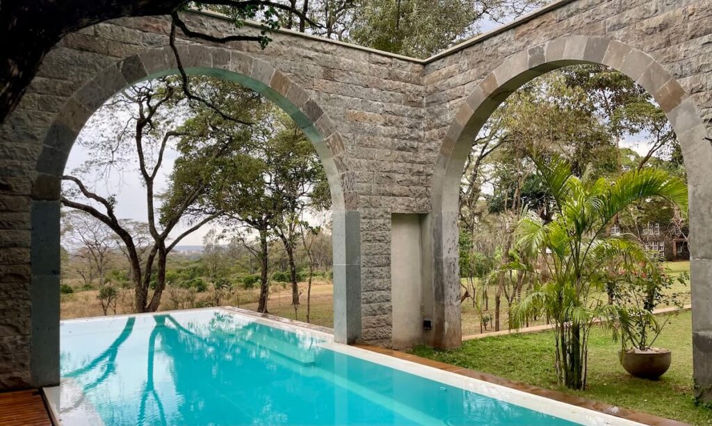 The Retreat pool with arch way and Giraffe Manor in the distance