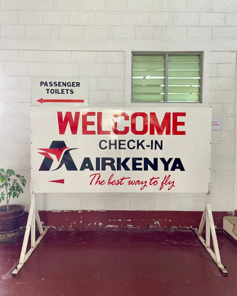 Air Kenya check-in sign with another sign towards passenger toilets at Nairobi Wilson airport