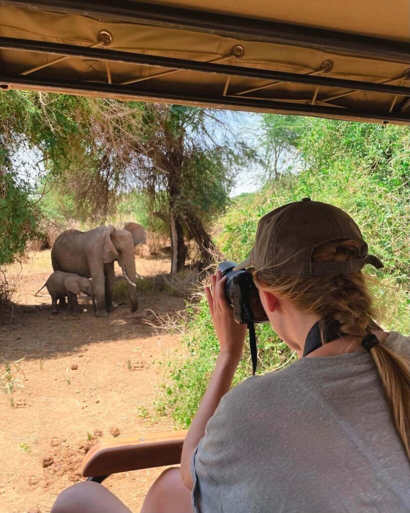 Samantha photographing Elephants in Samburu with linen shirt and cap