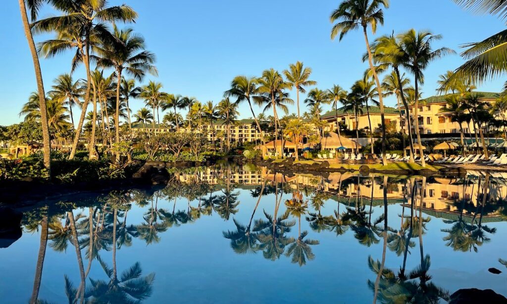 Grand Hyatt Kauai resort and pool surrounded by palm treed with blue sky