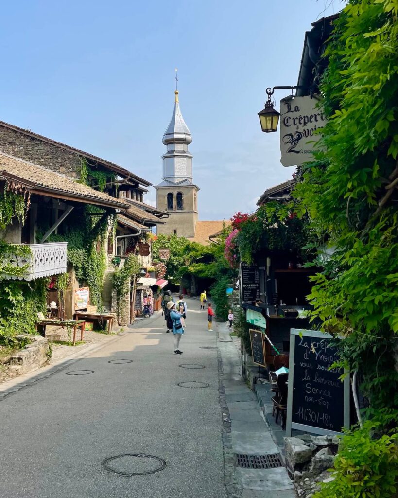 La Creperie d'Yvoire sign amongst vines with Yvoire church and bell tower
