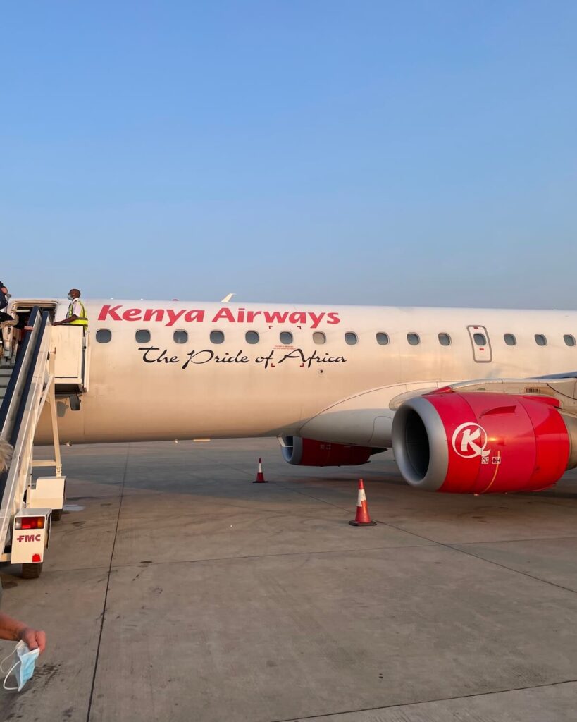 Kenya Airways plane with stairs to let passengers up and bright blue sky