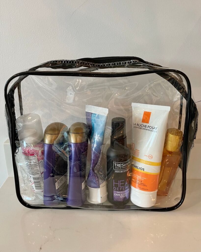 Selection of travel-sized toiletries in a clear plastic zip-up wash bag