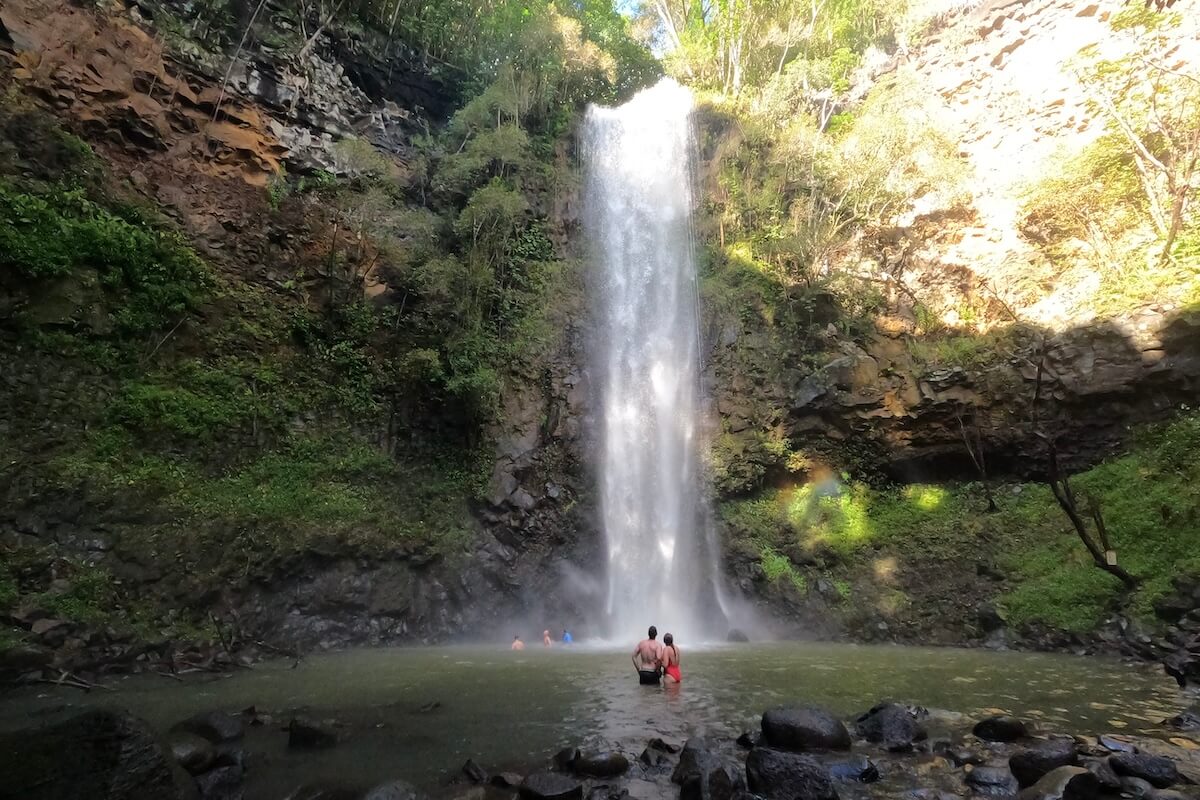 2 people standing at foot of waterfall on the Kayak to Secret Falls Kauai excursion