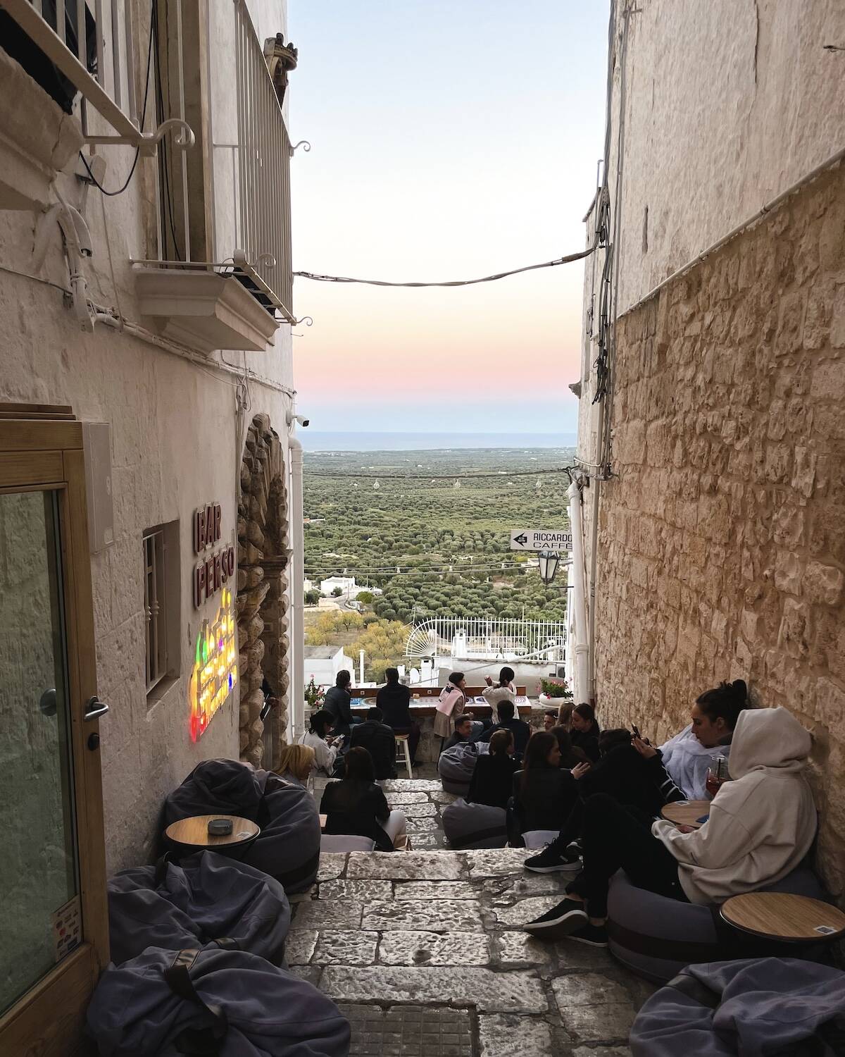 Side street in Ostuni filled with bean bags and a view of the sunset from Bar Perso