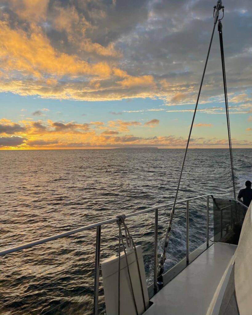 Orange and yellow sunset view across ocean while on Na Pali Coast boat tour