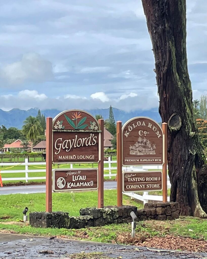 Wooden sign for Luau Kalamaku and Gaylord's Restaurant with lush green background