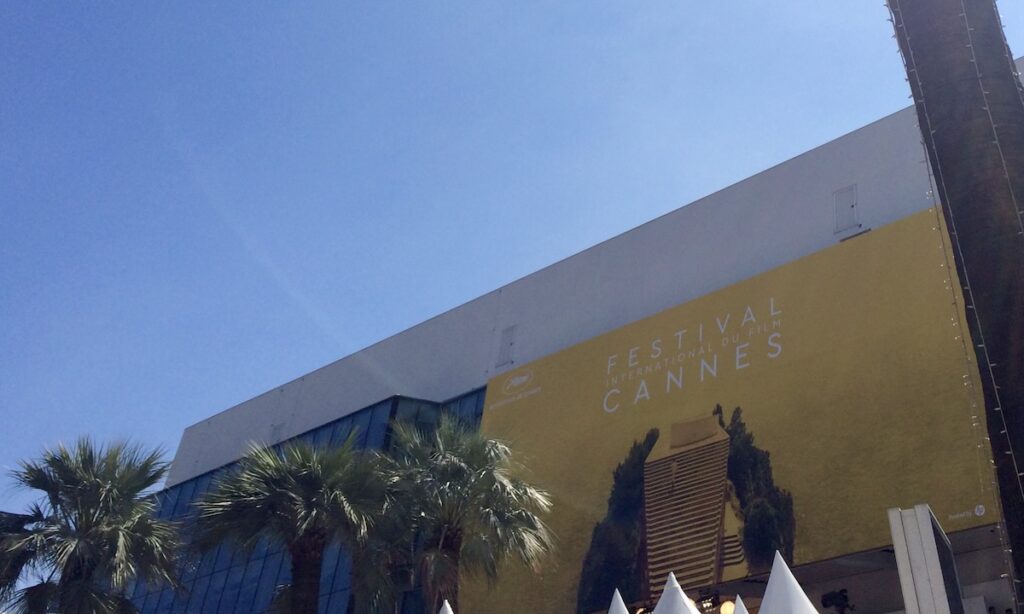 Cannes International Film Festival yellow sign stretched on building with palm trees