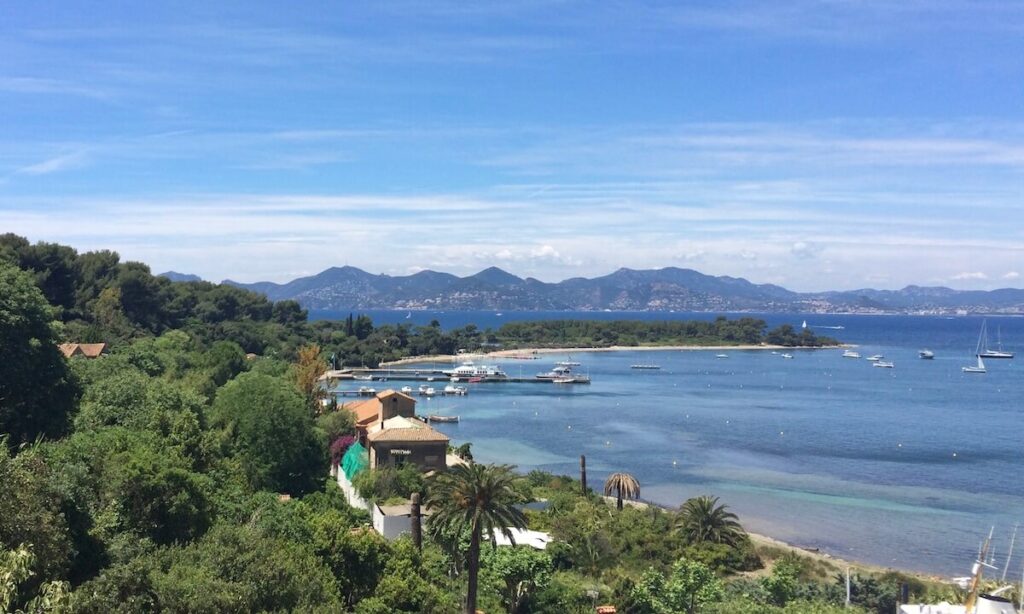 Ile Sainte Marguerite near to Cannes - crescent bay with boat and bright blue water