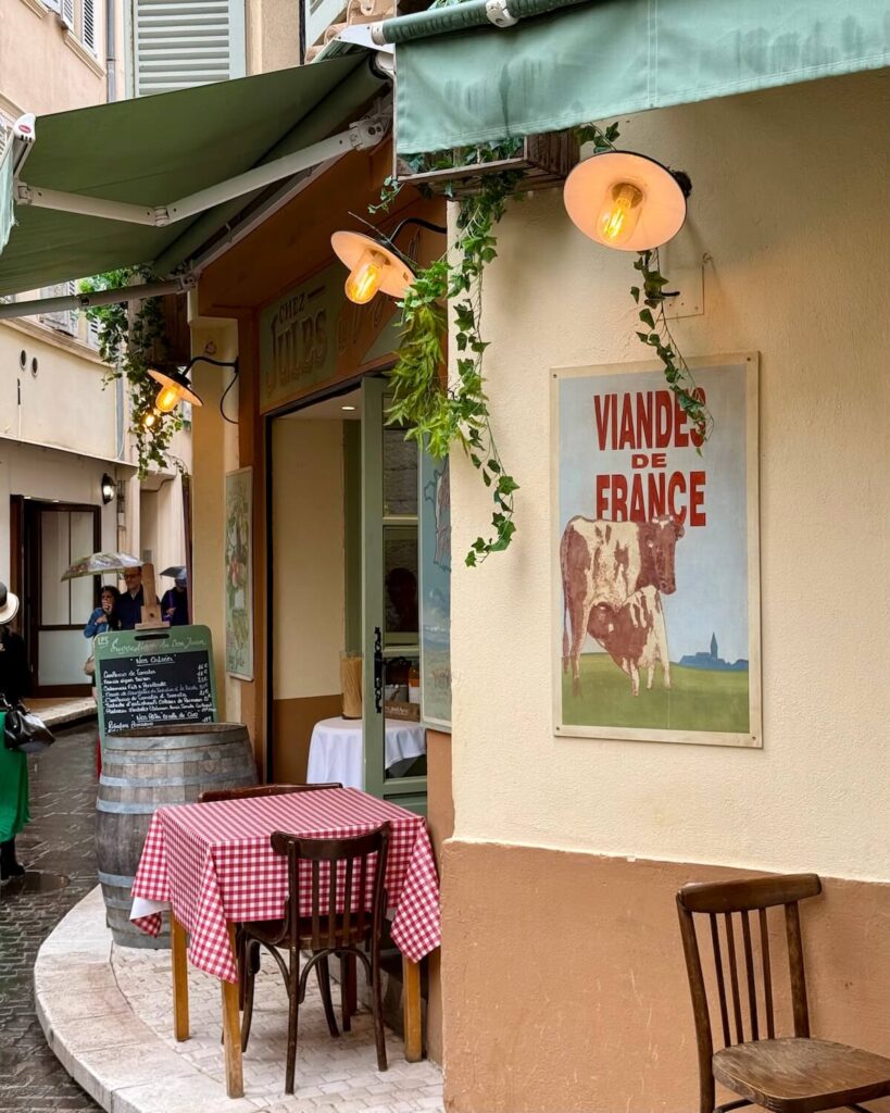 Restaurant in Antibes with orange walls and red checkered tablecloth and green awning