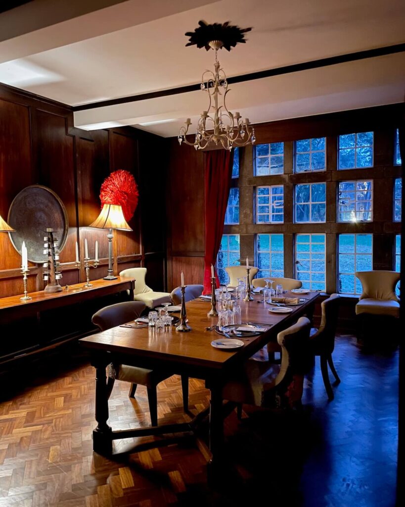 Table set for dinner at Giraffe Manor with brown wood furniture and faint light outside