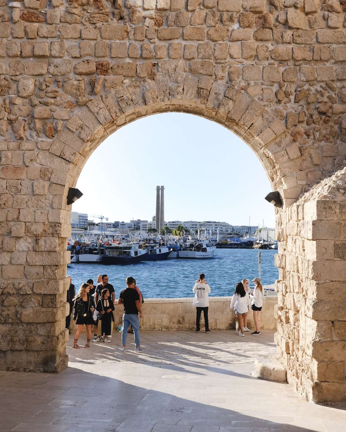 Monopoli - brick archway framing the port of Monopoli with groups of people looking out to the water