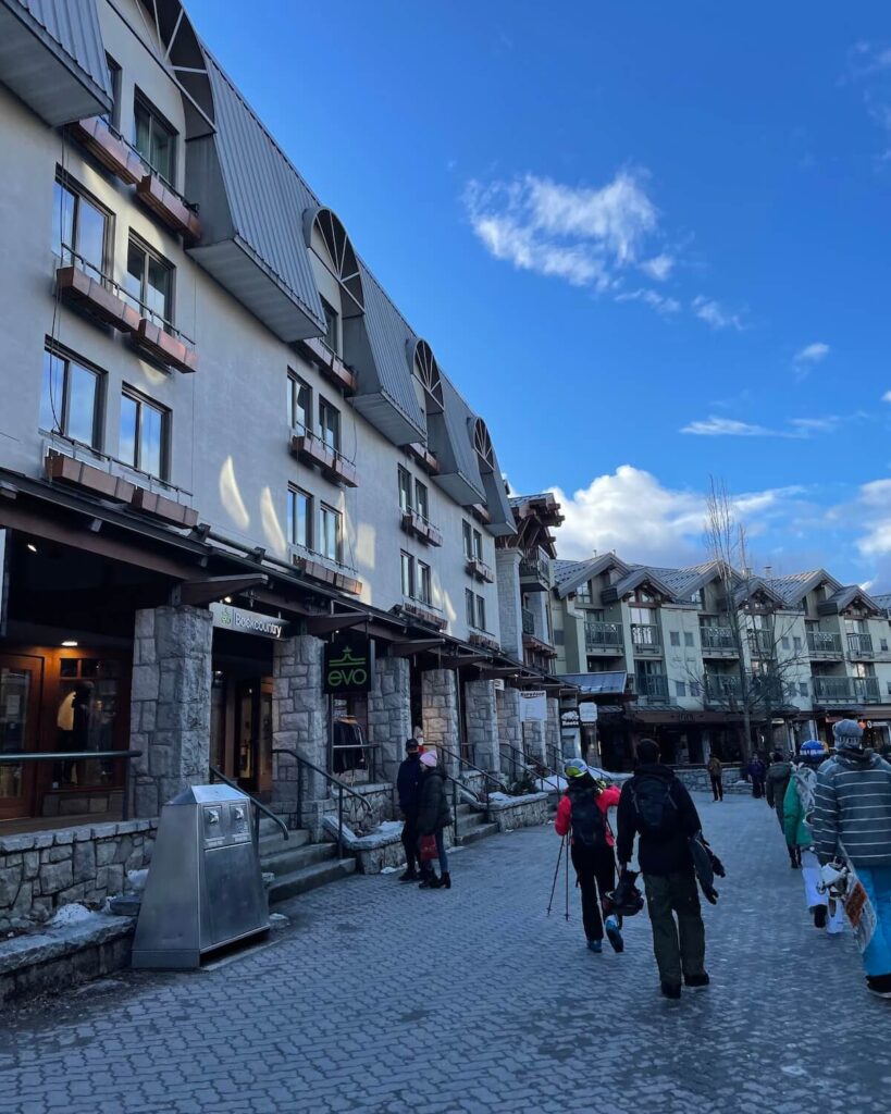 Whistler village - people carrying skis and snowboards as they walk through the accommodation