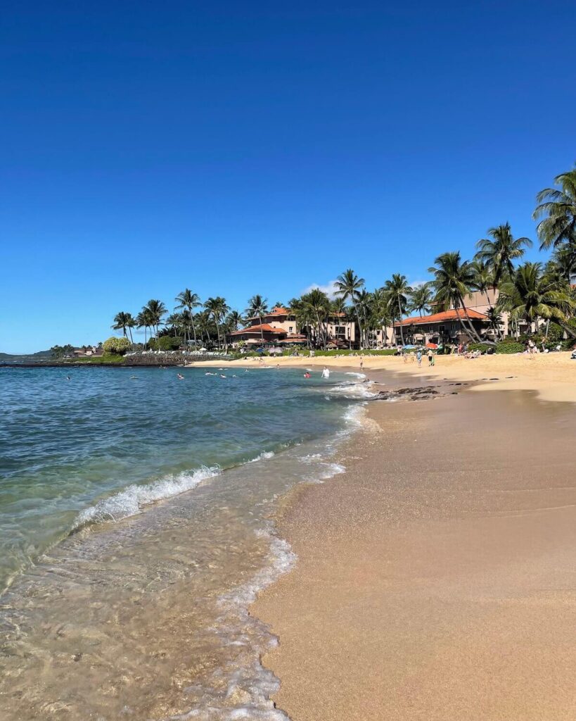 Sandy Poipu Beach Park in Kauai with beachfront buildings - one of best things to do in Poipu