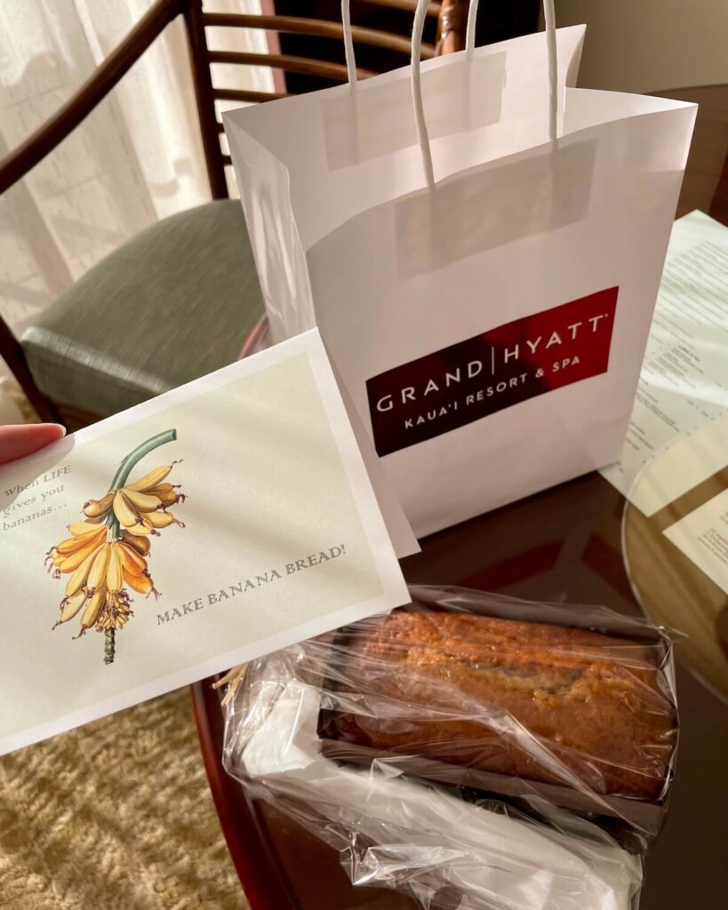 Banana bread wrapped in plastic with a Grand Hyatt paper bag and banana bread card on table