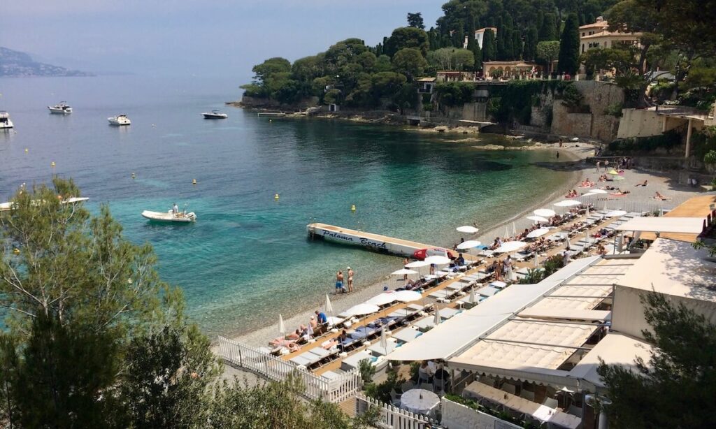 Paloma Beach in Saint-Jean-Cap-Ferrat with beach club set up and green blue water around bay