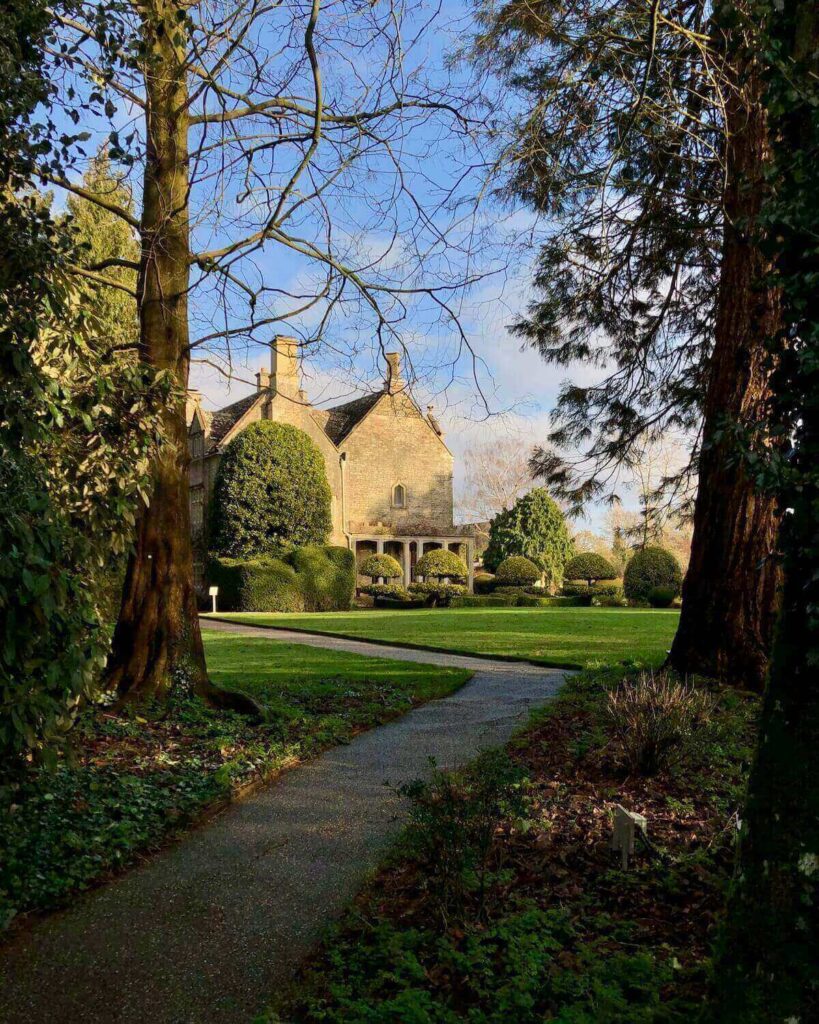 Barnsley House hotel in the Cotswolds - view of garden and building from under tree with blue sky