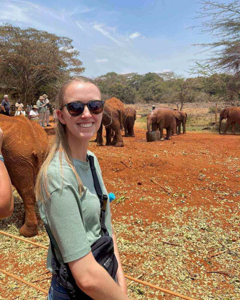 Sheldrick Elephant orphanage - Samantha wearing sunglasses and green t-shirt in front of baby elephants