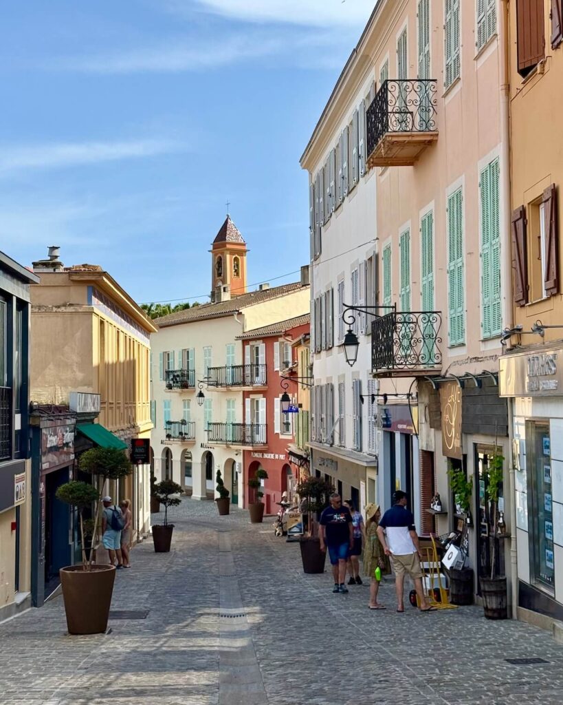 Colourful building on cobblestone street in Saint Jean Cap Ferrat with people looking in shop window