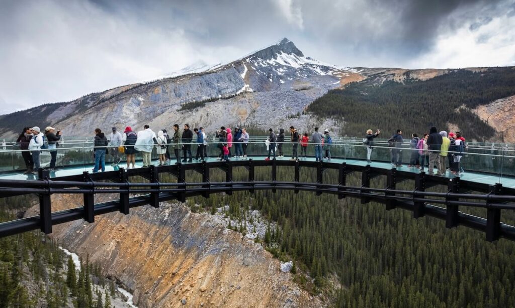 Columbia Icefield Skywalk - numerous people walking along elevated bridge walkway with mountain backdrop