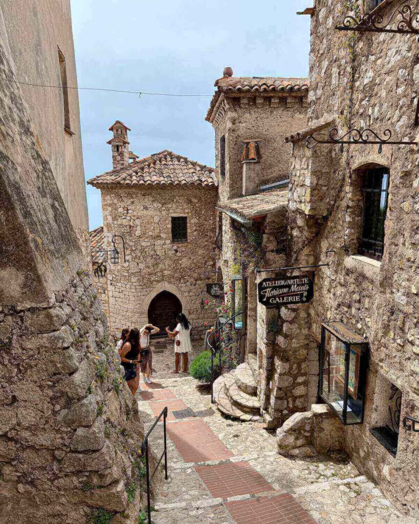 Cobblestone street with old brick building in Eze France and people gathered to take photos on grey day