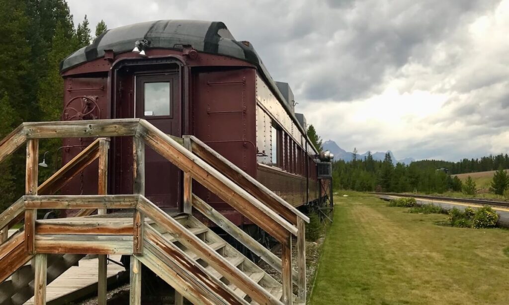 Station Restaurant in Lake Louise - old train carriage with steps to it on grass and mountains in distance