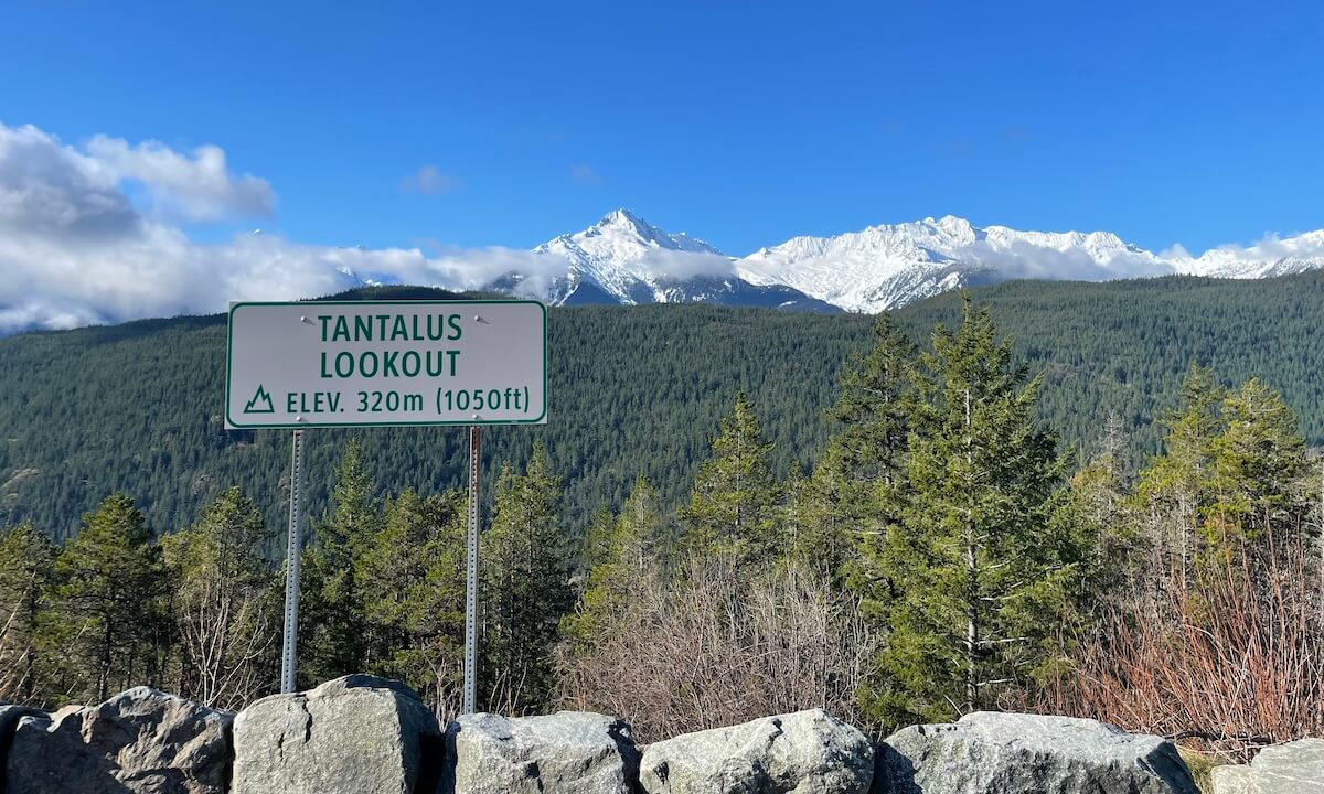 Sea to Sky Highway Vancouver to Whistler drive with a sign of Tantalus Looking and snowy mountains across a forest