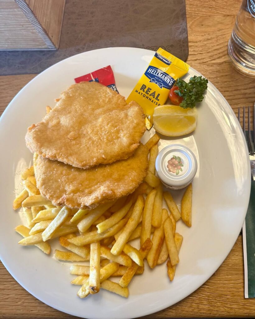 Wiener schnitzel on plate with fries and jar of sauce and lemon slice at mountain hut in Obergurgl Austria