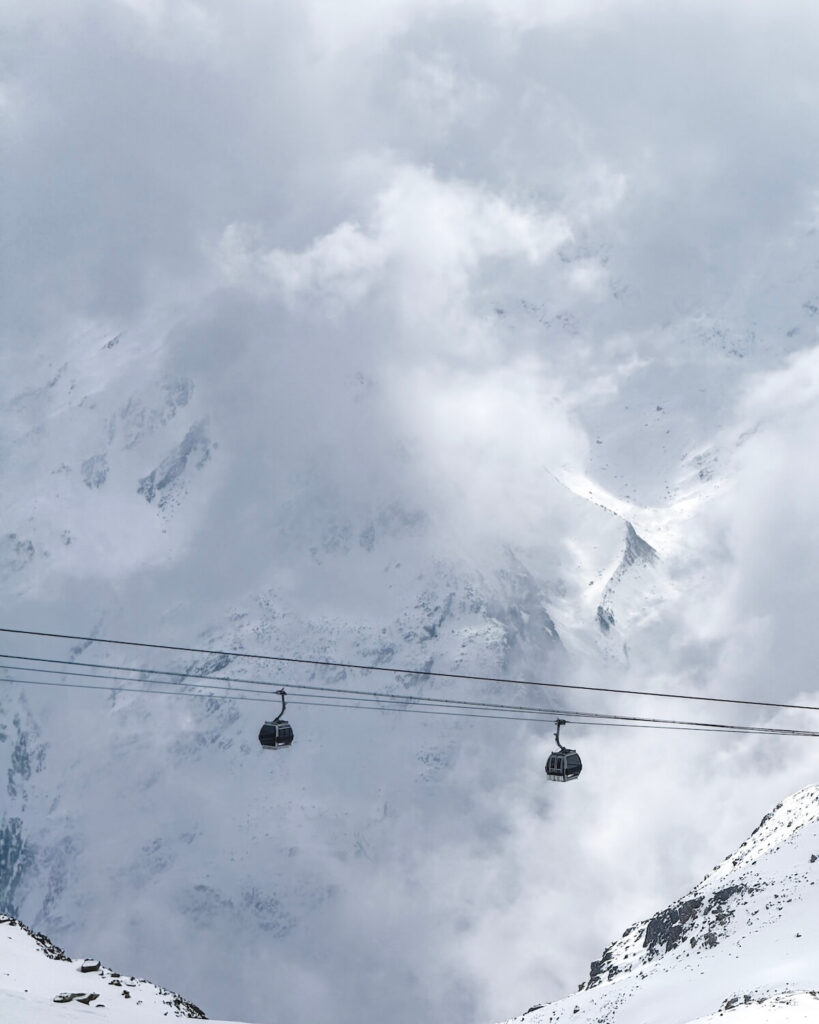 Gondolas travelling across mountain in the fog with a slight view of snowy mountain range in Obergurgl Austria