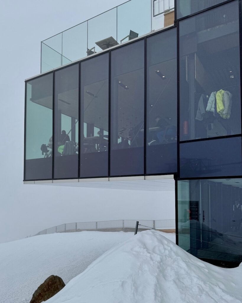 ice Q Restaurant on the top of a mountain on a cloudy day - you can see people dining wearing their ski clothes in Solden
