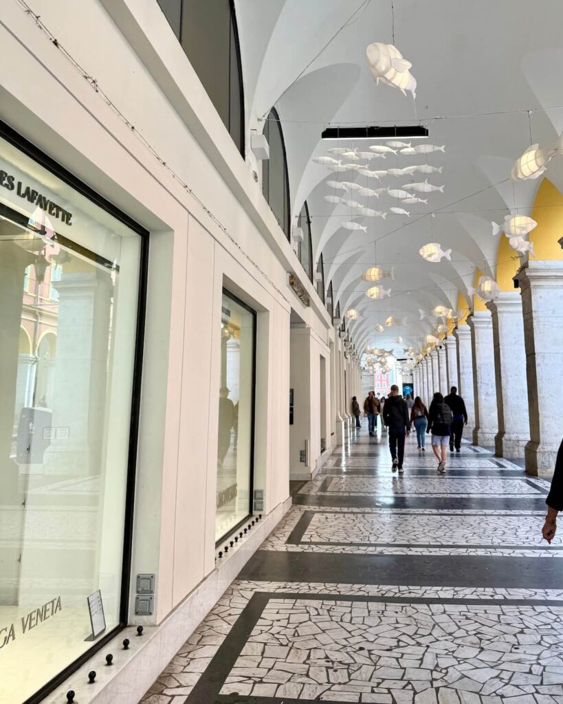 Galeries Lafayette department store in Nice from outside with ornamental fish hanging from archways and shop window in vision