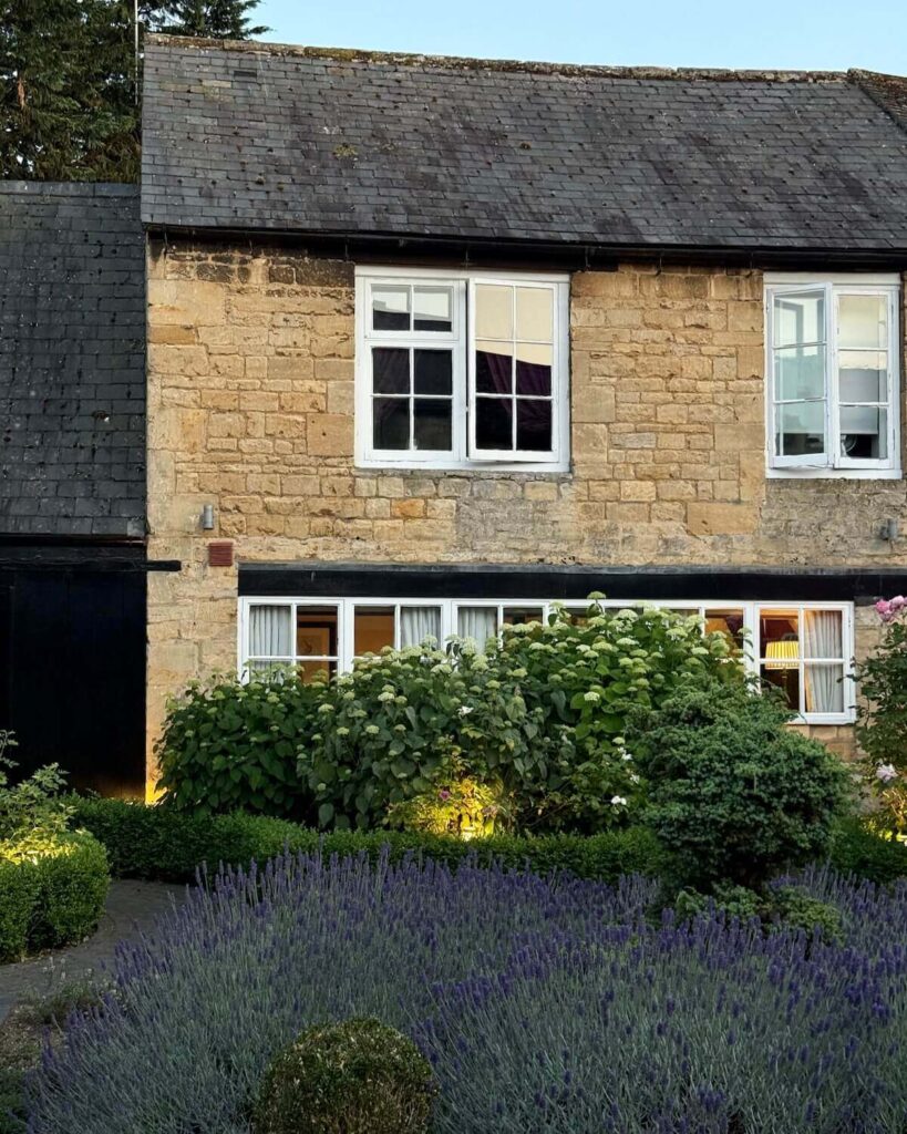 White Hart Royal hotel in Moreton-in-Marsh - yellow brick building with sunset lighting and lavender plants on the ground